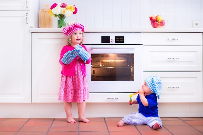 Two children in a kitchen with an oven