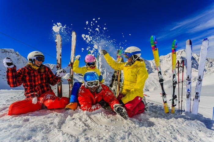 Four friends enjoying skiing and throwing snow