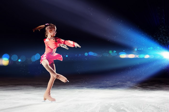 Little girl ice skating in a pink dress