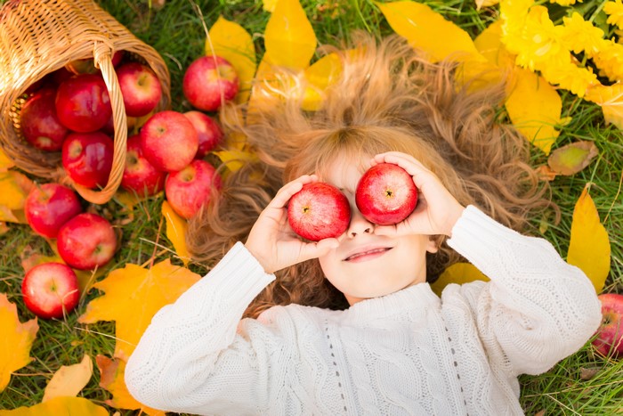 Girl with apples in autumn leaves