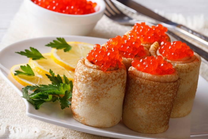 Pancakes with red caviar, lemon, and parsley