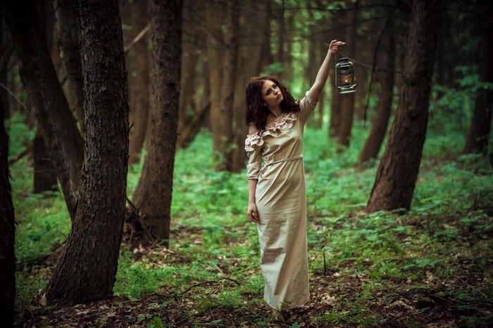 Woman holding a lantern in a forest
