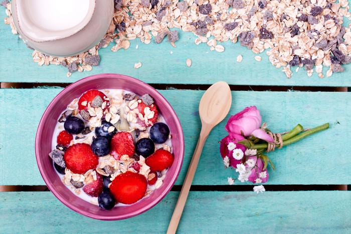 Muesli with berries and milk on wood planks