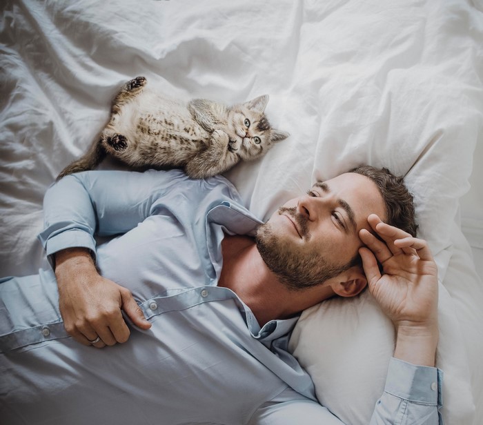 Man and kitten lying on a bed