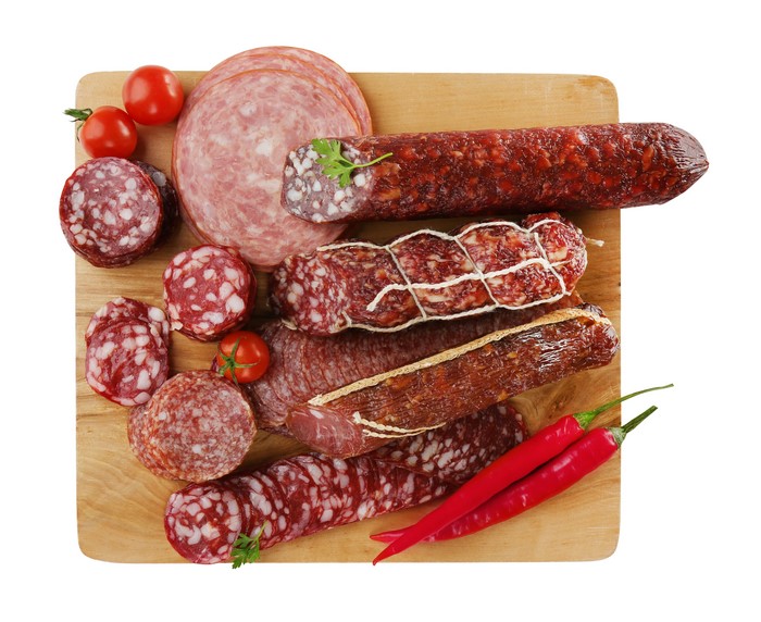 Assortment of Sausages, Tomatoes, and Chili Peppers on Cutting Board