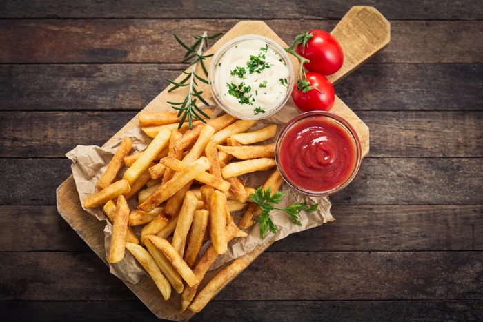 French fries with ketchup and mayonnaise on a cutting board