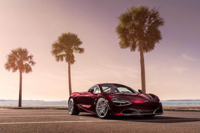 Red McLaren 720S Coupe parked by the ocean with palm trees