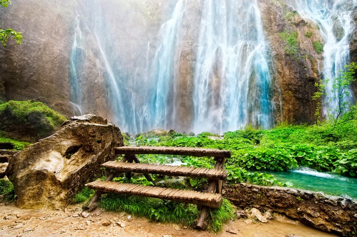 Waterfalls cascading over rocks with a wooden bench