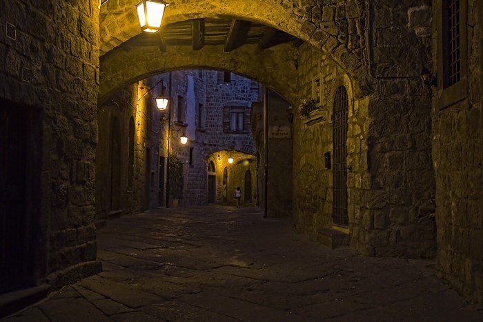 Street at night with stone archway and lanterns in Viterbo, Italy