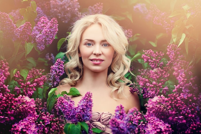 Blonde girl surrounded by lilacs
