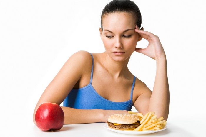 Woman choosing between apple and fast food