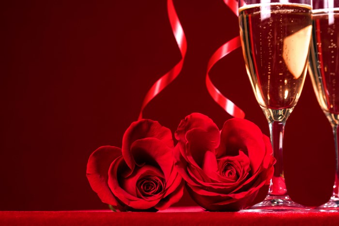 Two red roses and champagne glasses with ribbons