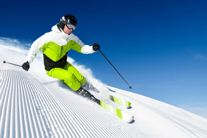 Man skiing down a groomed slope in winter