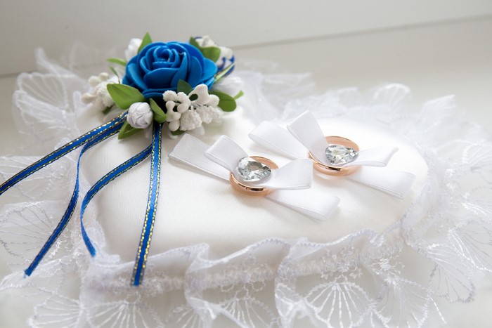 Wedding ring pillow with rings and blue rose decoration