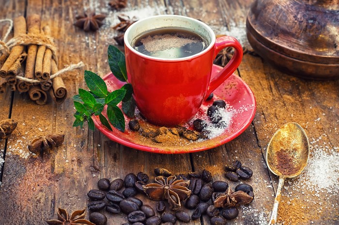 Red coffee cup with cinnamon and coffee beans