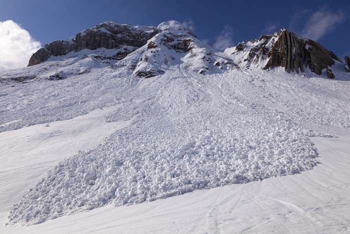 Avalanche on a snowy mountain under a blue sky