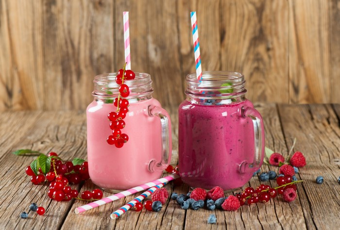 Two berry smoothies in mason jars with fresh berries