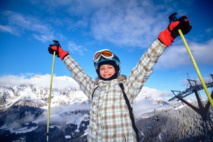 Boy skiing with arms raised on a snowy mountain