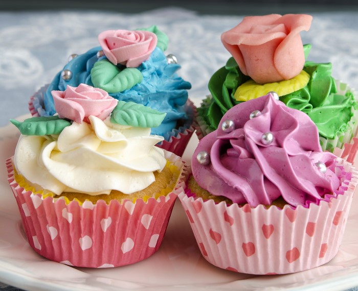 Four decorated cupcakes with frosting roses