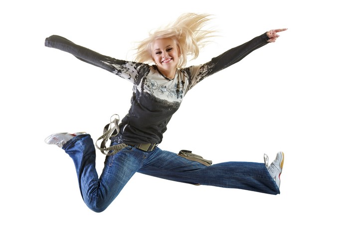 Blonde girl jumping in jeans on white background