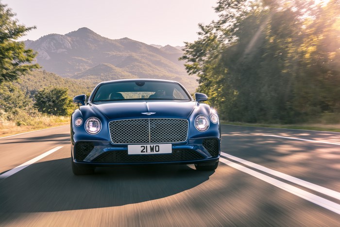 Blue Bentley Continental GT driving on a mountain road