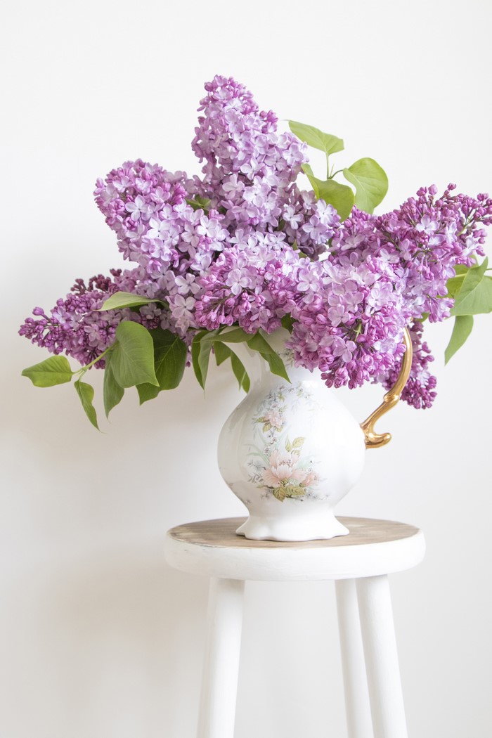 Bouquet of lilacs in a decorative vase on a stool