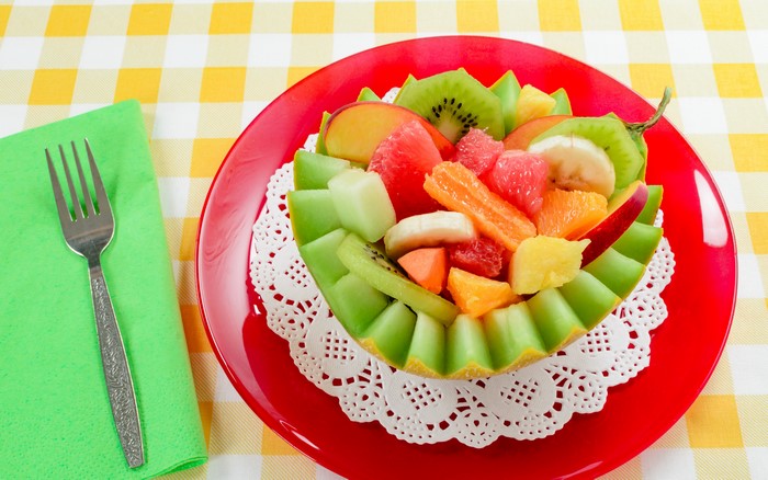 Fruit salad in a melon bowl on a red plate