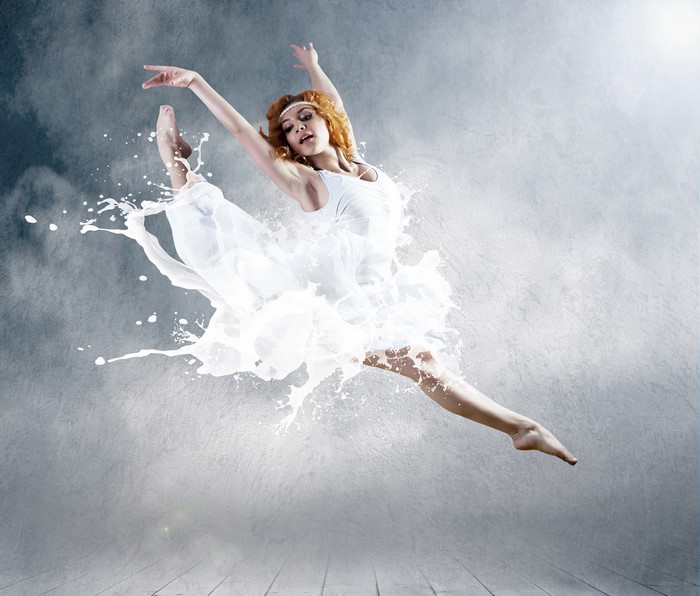 Redhead ballerina jumping in milk splash