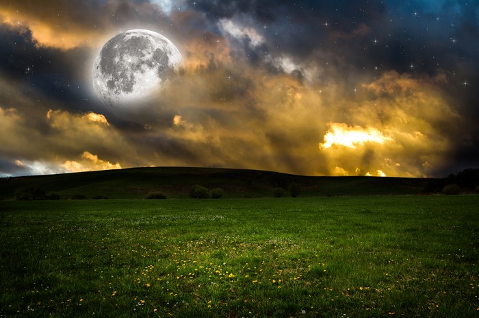 Full moon over a grassy hill at night