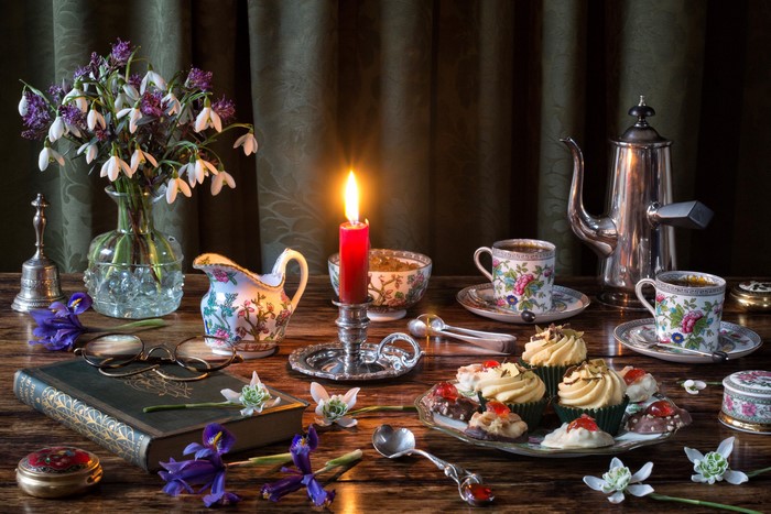 Still-life with snowdrops, cakes, coffee, and a candle