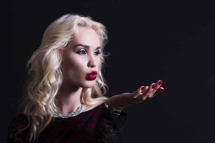 Blonde woman blowing a kiss with jewelry
