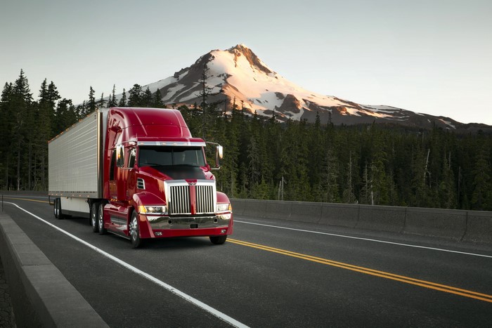 Red Western Star 5700XE Sleeper Cab Truck on Road with Mountain