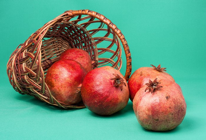 Pomegranates spilling from a wicker basket