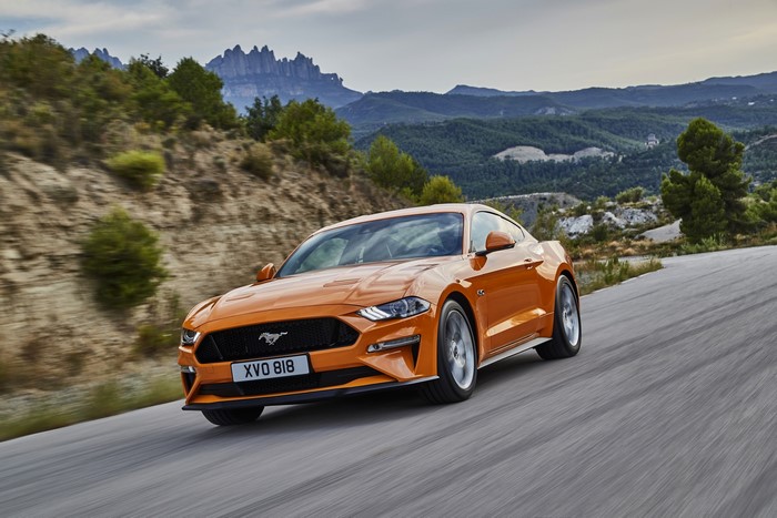 Orange Ford Mustang GT driving on a mountain road