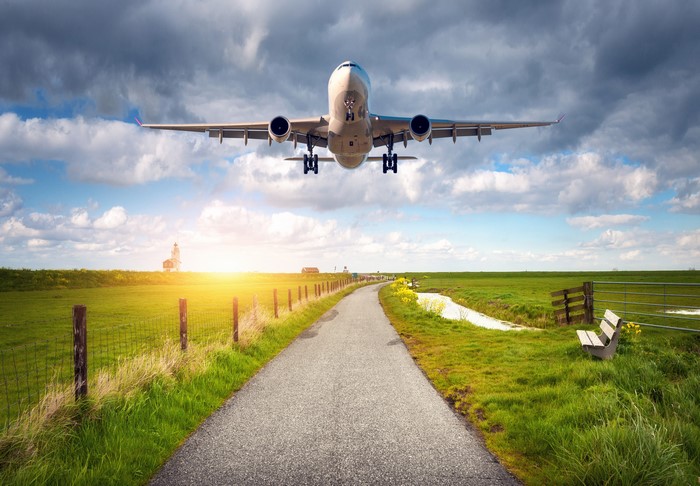 Airplane flying over a rural landscape with a road