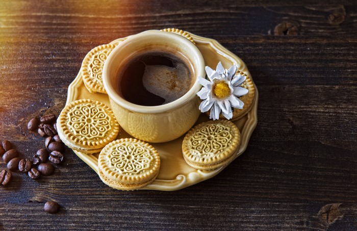 Coffee cup with cookies and coffee beans on wood