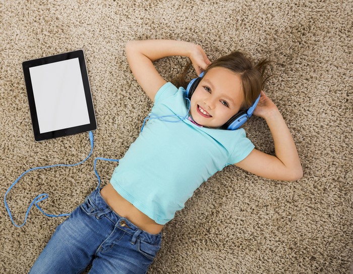 Girl with headphones and tablet on carpet