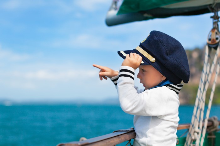 Boy in captain's hat on a sailboat
