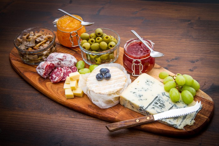 Cheese and charcuterie board with olives, jam, and mushrooms