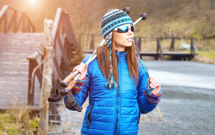 Woman with ski poles wearing winter hat and jacket
