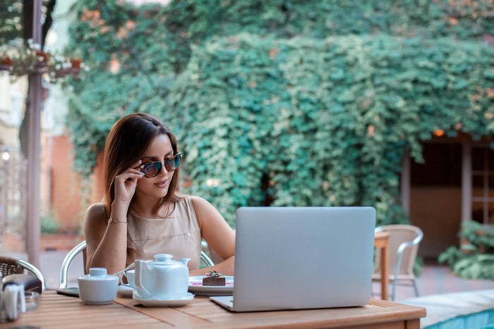Woman in sunglasses using a laptop at a cafe