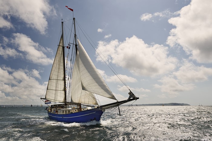 Blue sailboat sailing on the sea under clouds