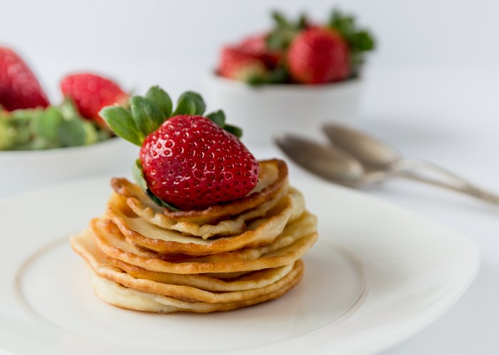 Stack of pancakes with strawberry and spoons