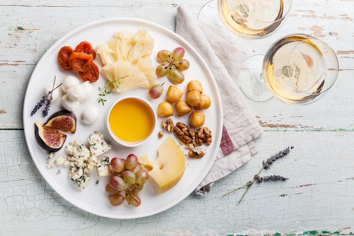 Cheese board with wine, grapes, figs, nuts, and honey
