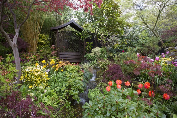 English garden with a wooden gazebo and waterfall