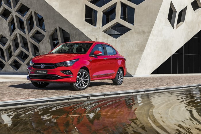 Red Fiat Cronos sedan parked near a modern building