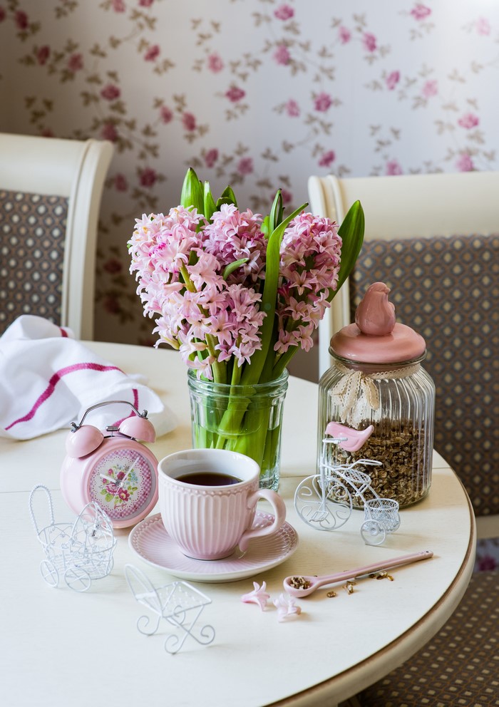 Pink hyacinths, coffee cup, and alarm clock on a table