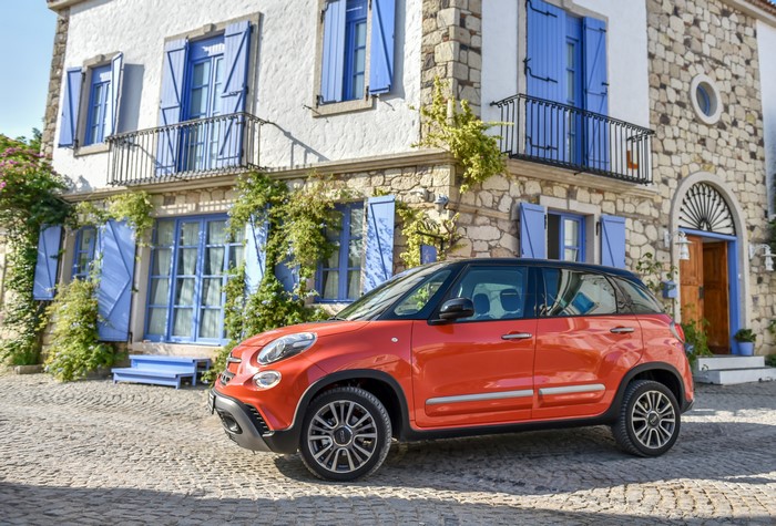 Orange Fiat 500L Cross parked in front of a stone house