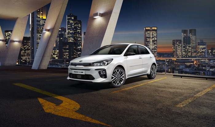 White Kia Rio parked in a city at night