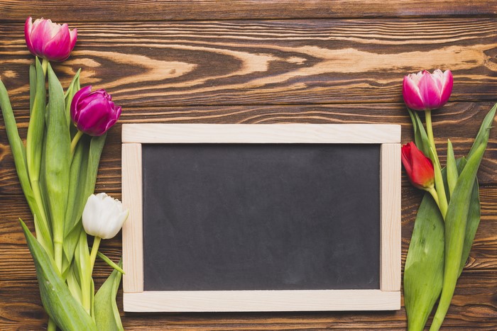 Tulips on a wooden background with a chalkboard
